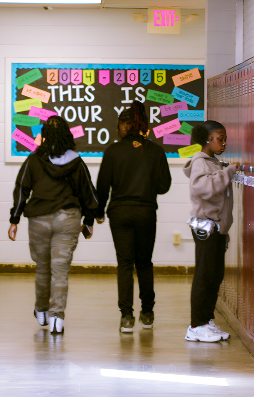 student using locker and students walking to class