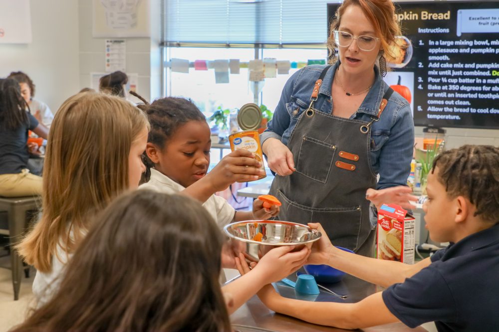 A teacher helps students bake
